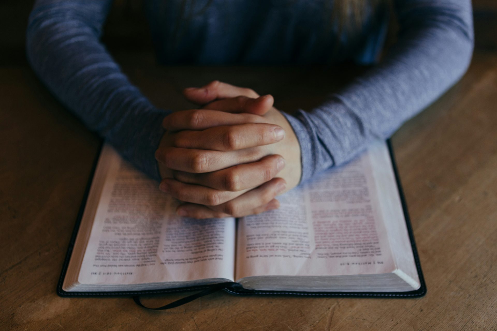 Hands clasped on open book